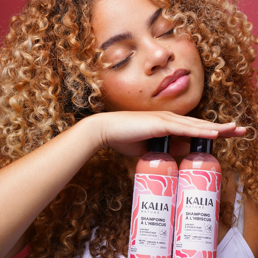 Photo d'un modèle avec le nouveau shampoing liquide à l'hibiscus de Kalia Nature